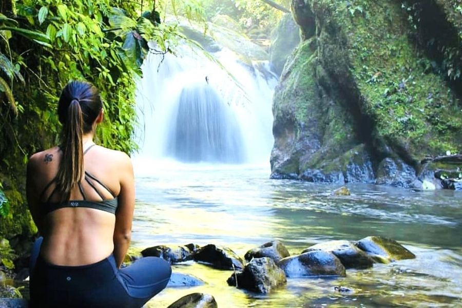 Besucherin am Becken eines Wasserfalls im Nebelwald bei Mindo